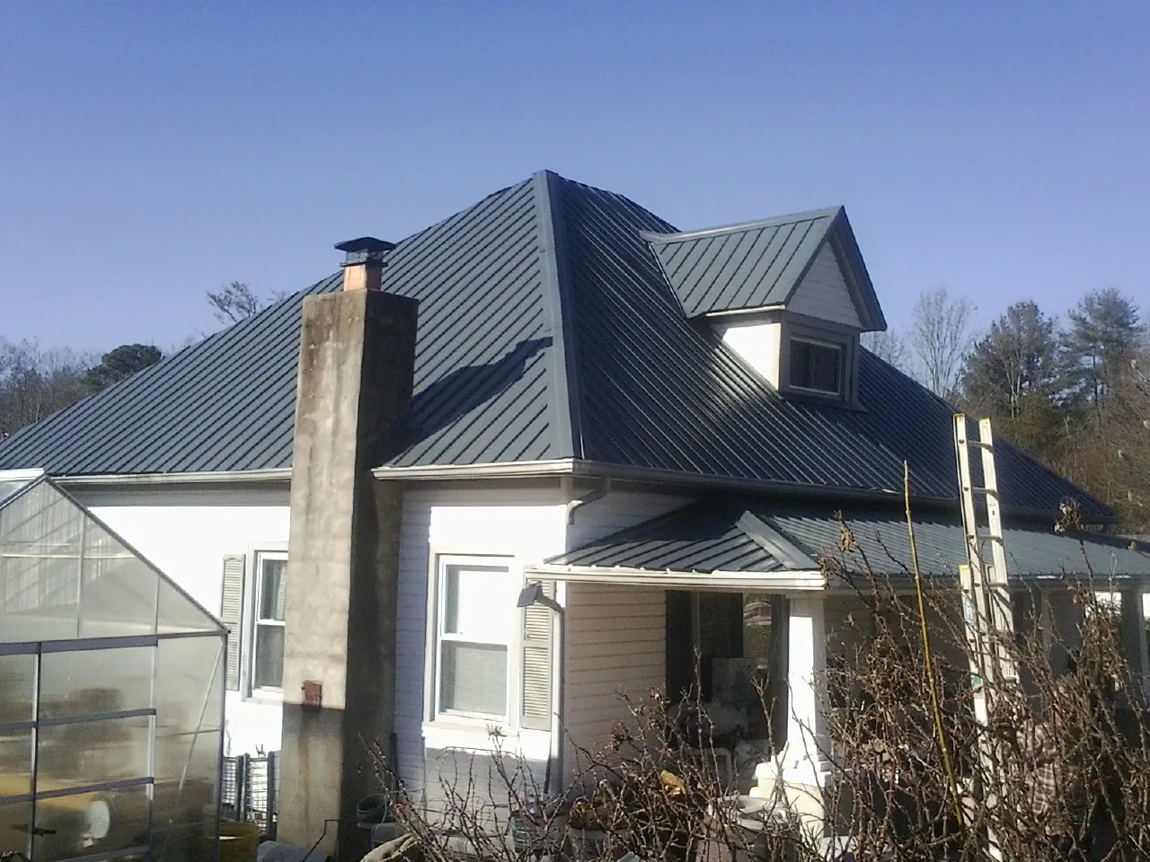 Dark blue standing seam metal roof on a white farmhouse with dormer — Slate & Tile Roof Repair by Roofing Brothers in Bryans Road