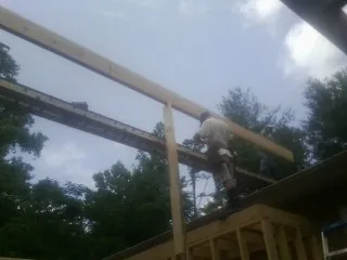Carpenter setting a ridge beam over a new addition frame — Ice Dam Removal by Roofing Brothers in Bryans Road