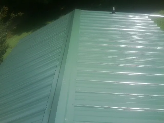 New green metal panels meeting at the ridge of a roof — Flat Roof Repair work by our crew in Bryans Road