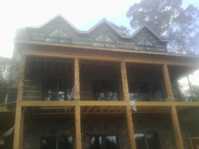 Dormers and porch framing on a large log home under construction — Roof Coating work by our crew in Bryans Road