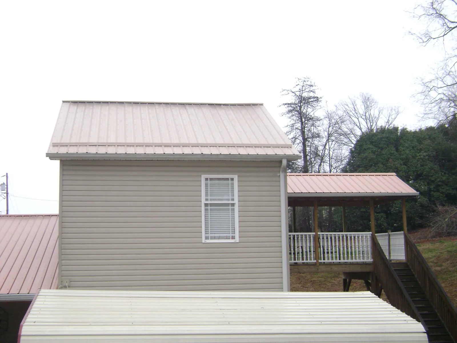 Tan metal roofs on a two story addition and attached porch, from a Roof Replacement job in Bryans Road