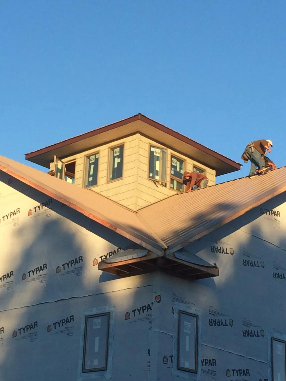 Roofers working around a rooftop cupola on a new metal roof at sunset — Roof Waterproofing in Bryans Road by Roofing Brothers